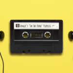 Cassete tape labeled "Angie's 'In the zone' Playlist" with earbuds on either side and a yellow background