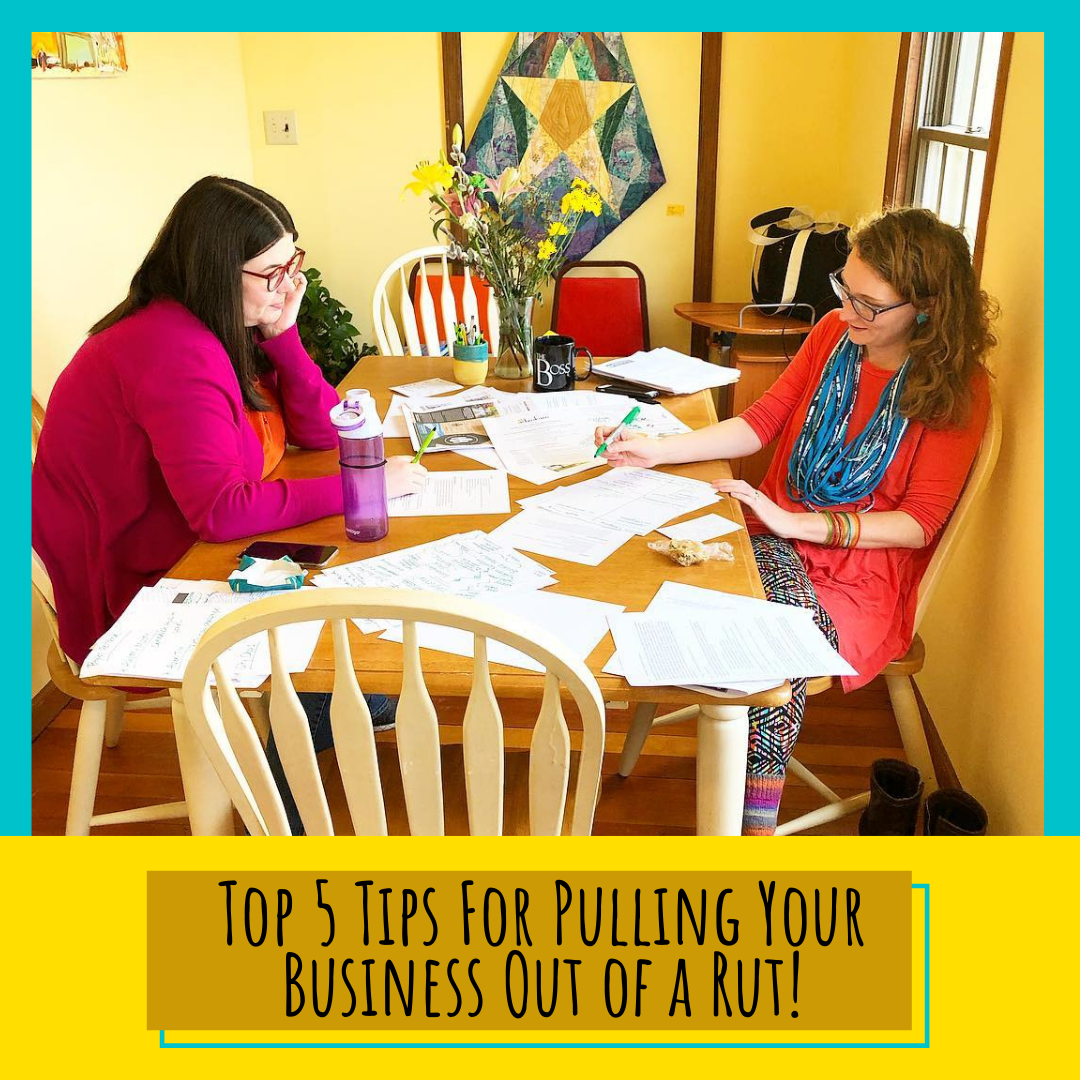 Two women sitting at a table with a bunch of papers spread out. Text, "Top 5 tips for pulling your business out of a rut!"